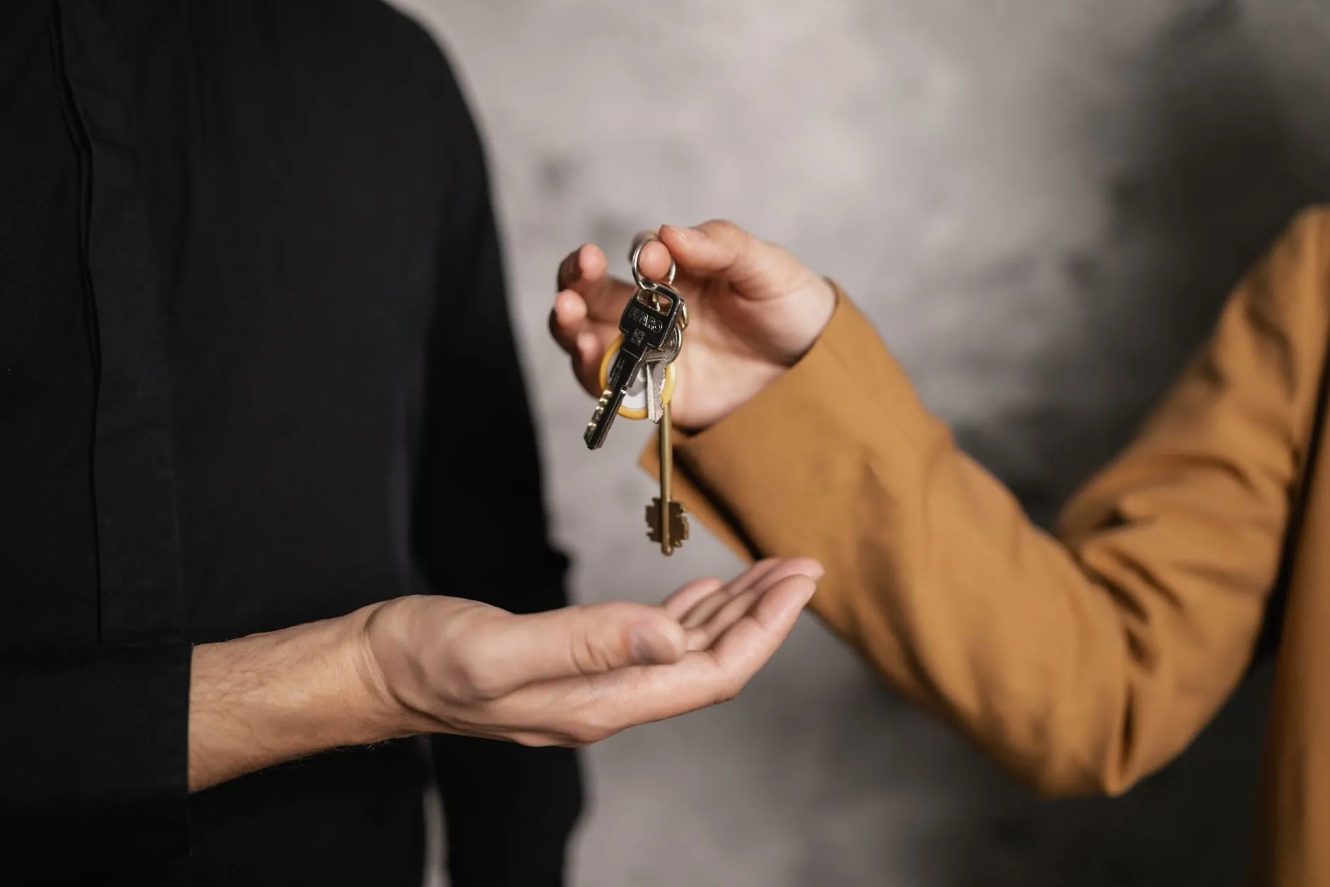 Keys being handed from one person to another over an open palm