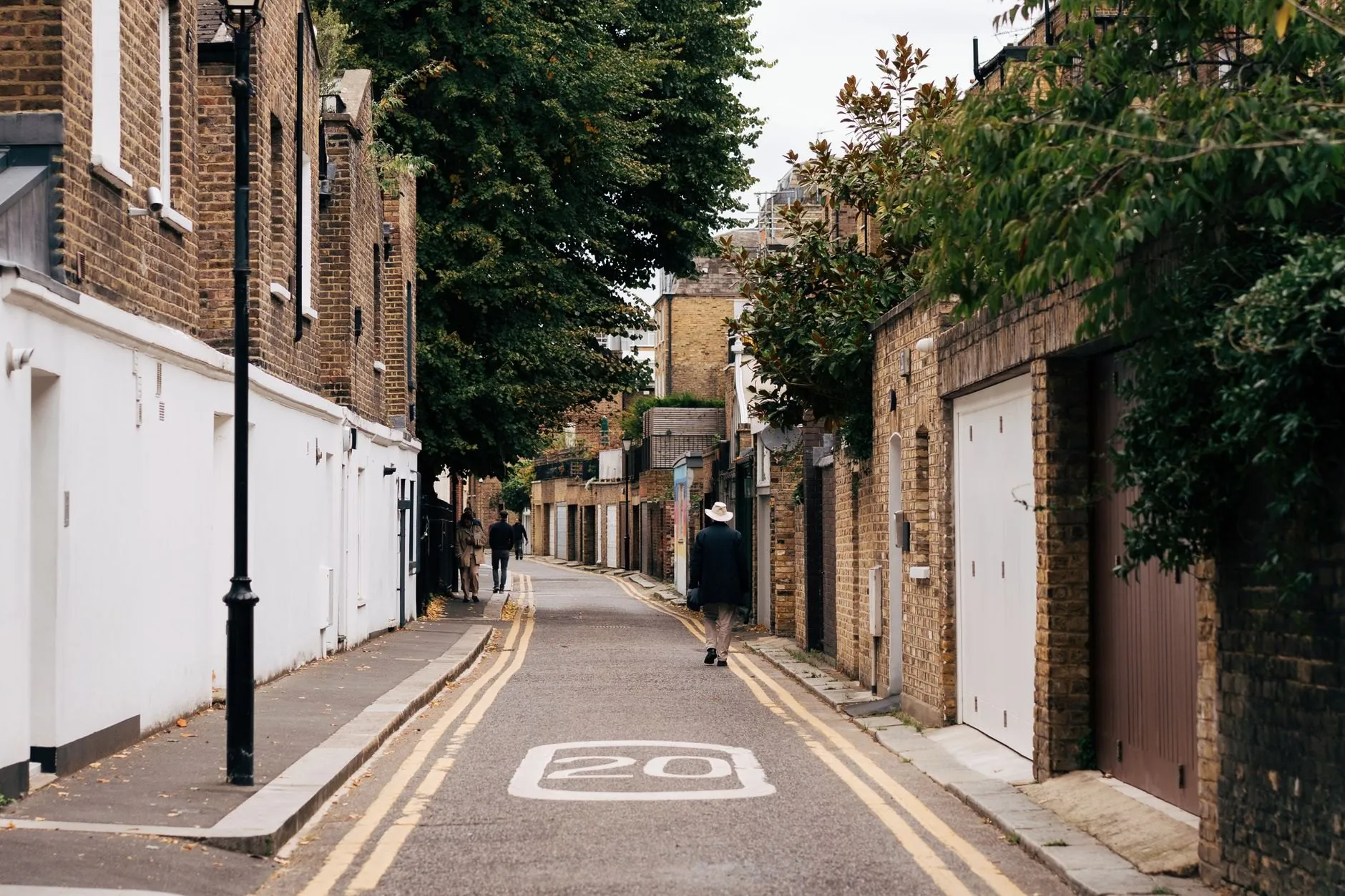 A narrow Old Town street with brick houses, white garage doors and a lamp post